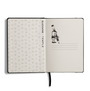 An open notebook or journal on a white background, showing the black cover edge and ribbon bookmark. The left page has a light gray patterned interior with vertical text reading 'BLACKWING TEMPLE'.
